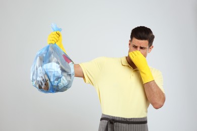 Photo of Man holding full garbage bag on light background