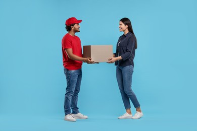 Photo of Smiling courier giving parcel to receiver on light blue background