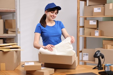 Post office worker packing parcel at wooden table indoors