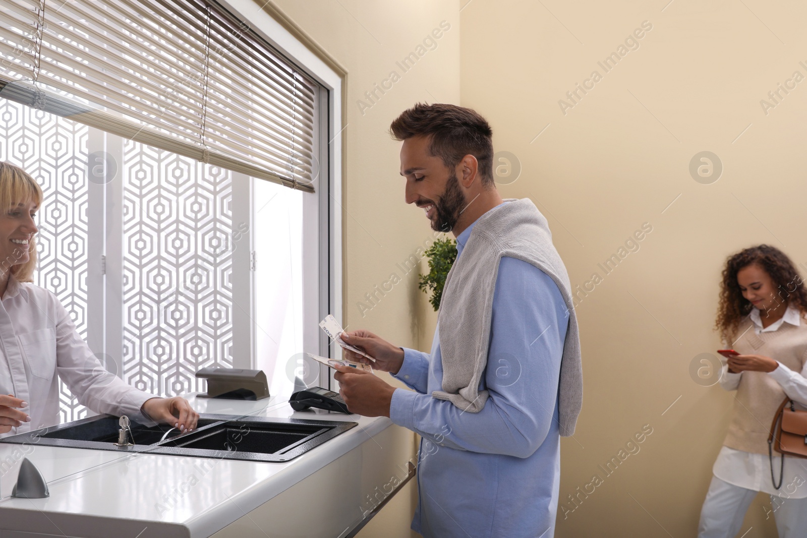 Photo of Man with money at cash department window in bank. Currency exchange