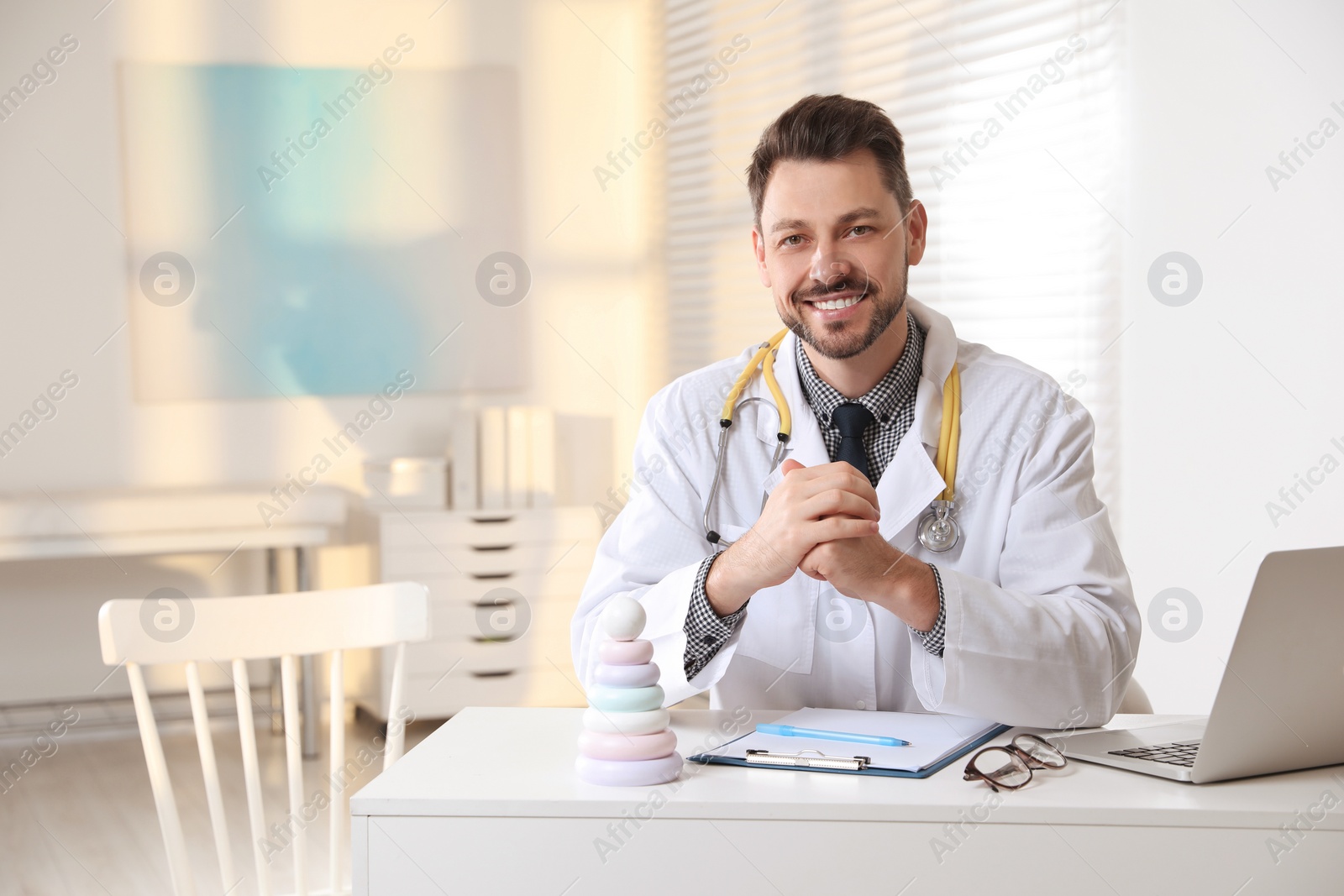 Photo of Pediatrician with stethoscope at table in clinic