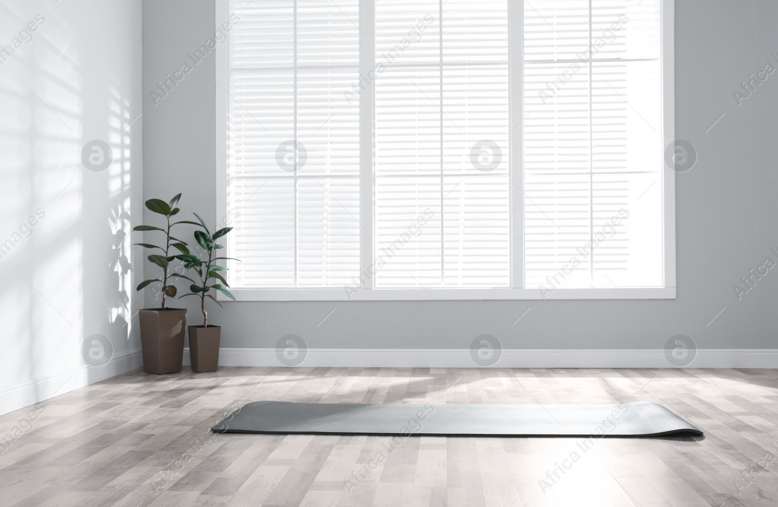 Photo of Unrolled grey yoga mat on floor in room