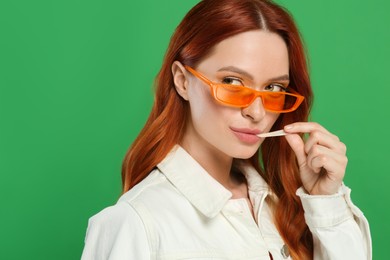 Portrait of beautiful woman in sunglasses with bubble gum on green background. Space for text
