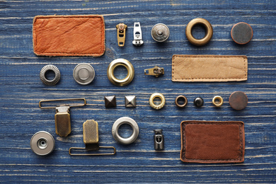 Photo of Flat lay composition with garment accessories for jeans on blue wooden background