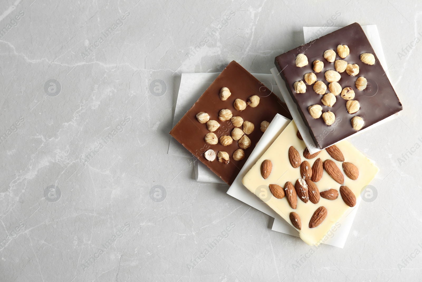 Photo of Different chocolate bars with nuts on grey background