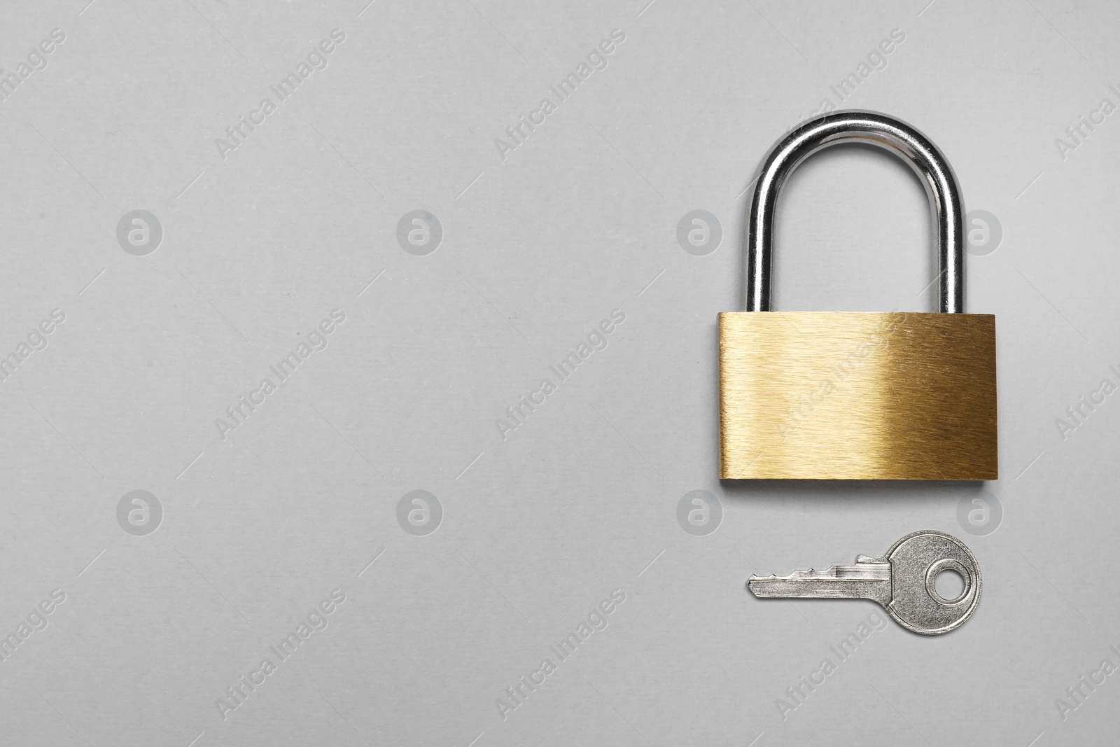 Photo of Steel padlock with key on grey background, top view. Space for text