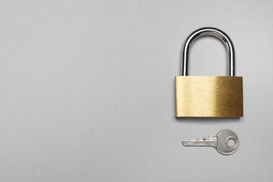 Photo of Steel padlock with key on grey background, top view. Space for text