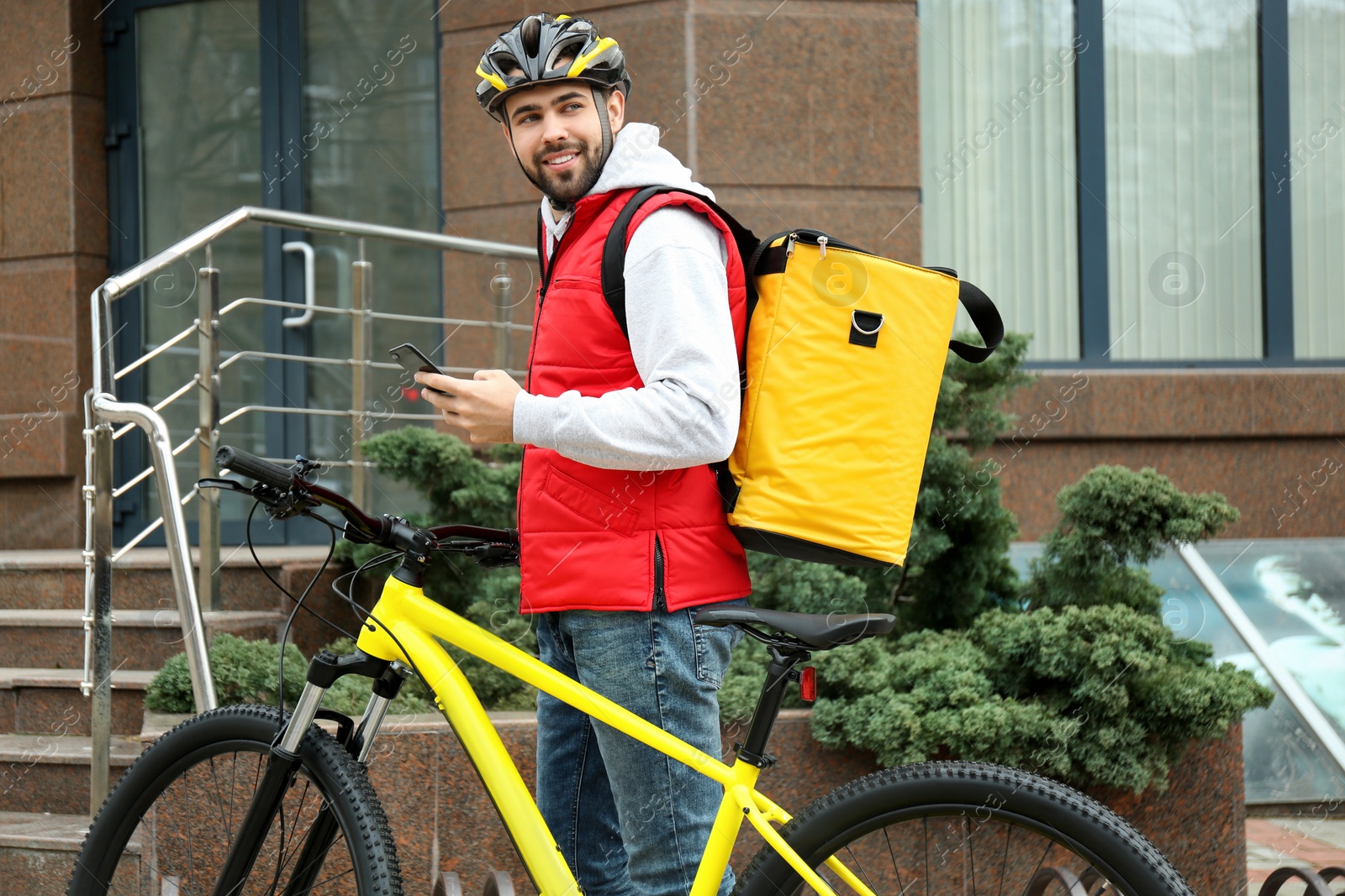 Photo of Courier with thermo bag, bicycle and mobile phone on city street. Food delivery service