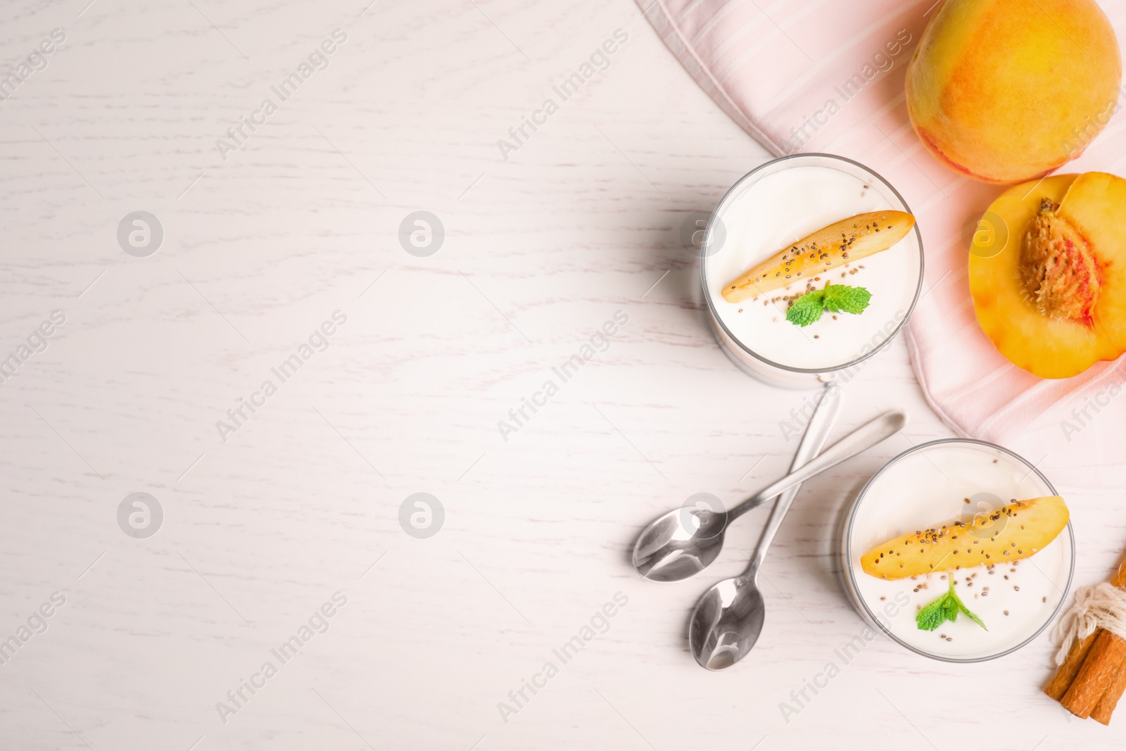 Photo of Tasty peach dessert with yogurt and chia seeds served on white wooden table, flat lay. Space for text