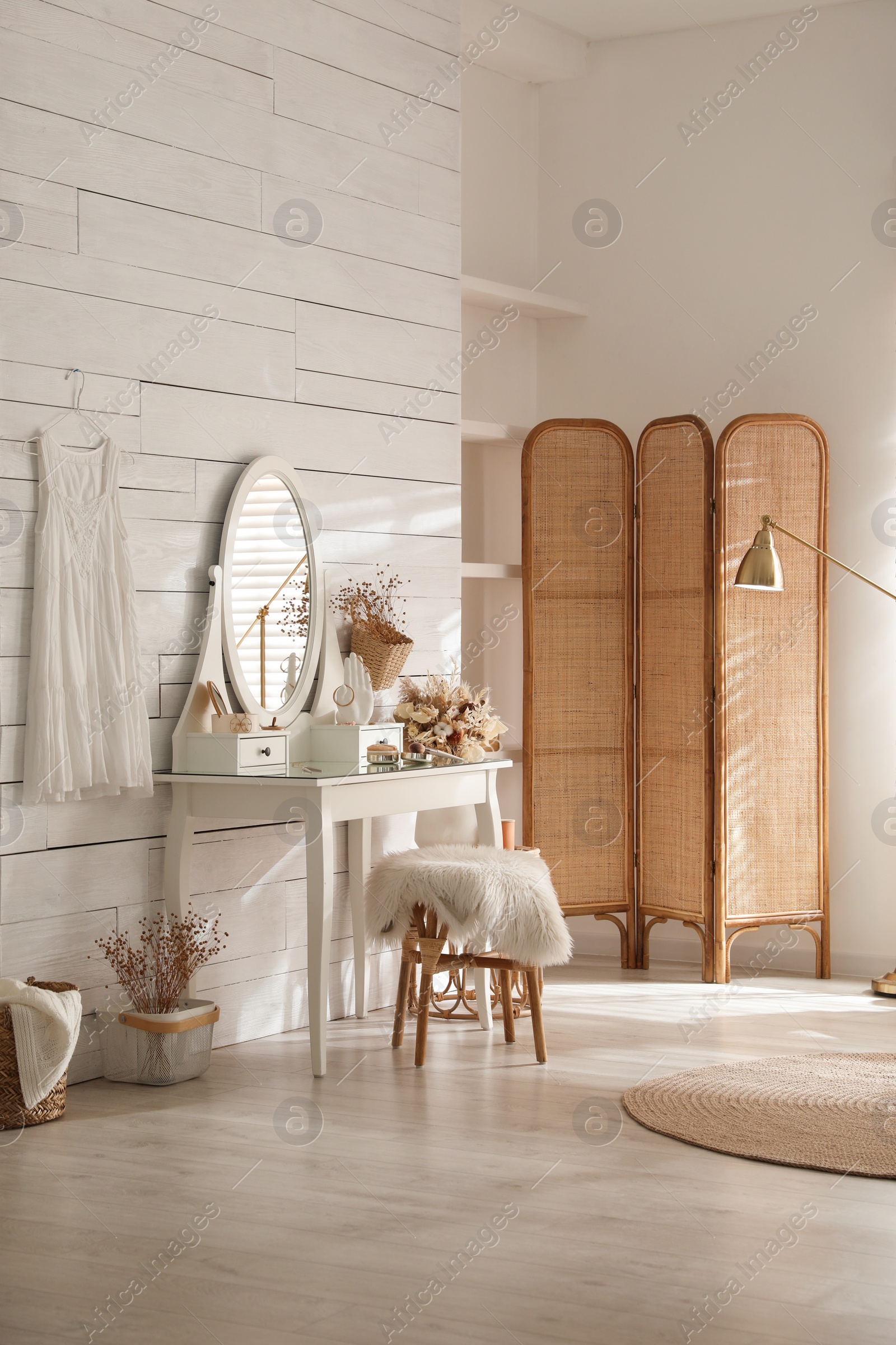 Photo of Wooden dressing table with decorative elements and makeup products in room. Interior design