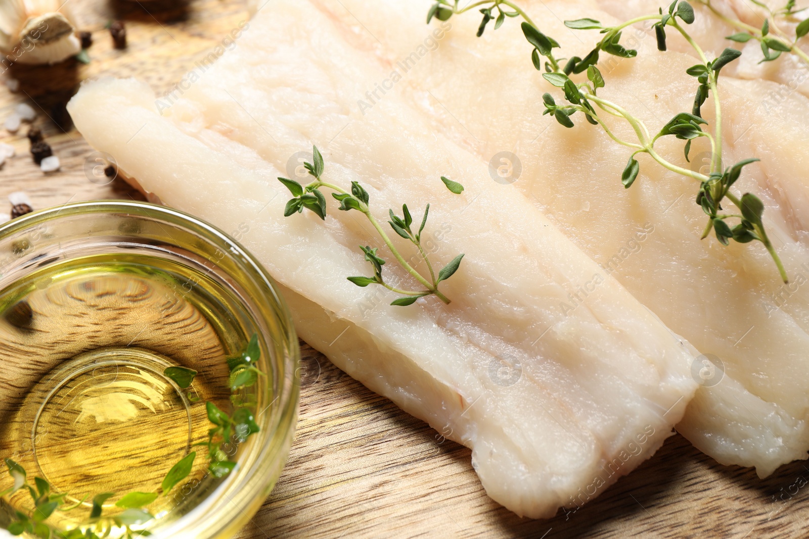 Photo of Raw cod fish, microgreens and oil on wooden table, closeup