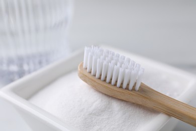 Photo of Bamboo toothbrush and bowl of baking soda on table, closeup