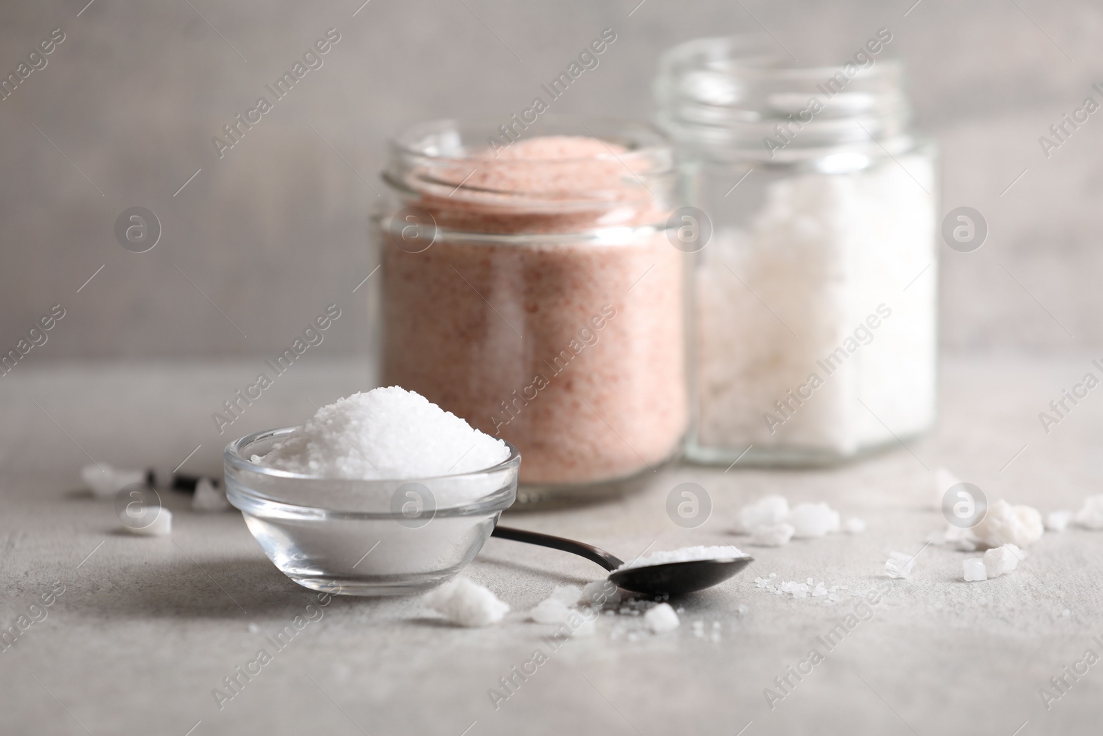 Photo of Different natural salt on grey table, closeup