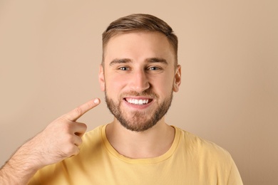 Photo of Young man with healthy teeth on color background