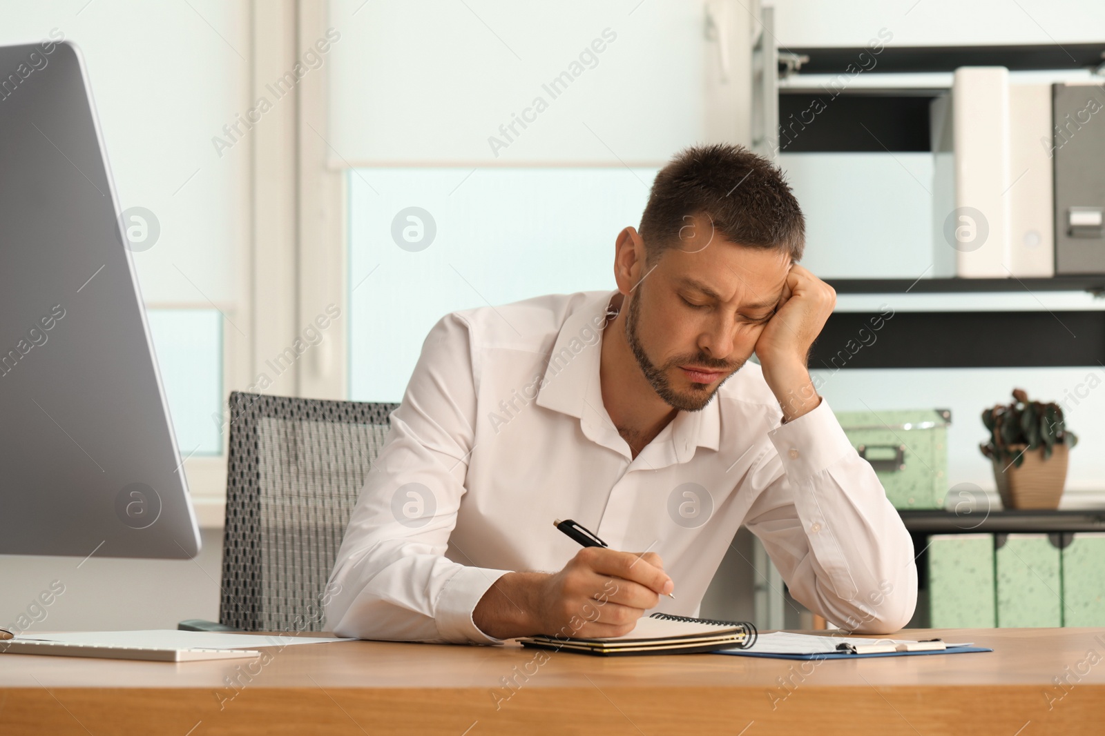 Photo of Sleepy man snoozing at workplace in office