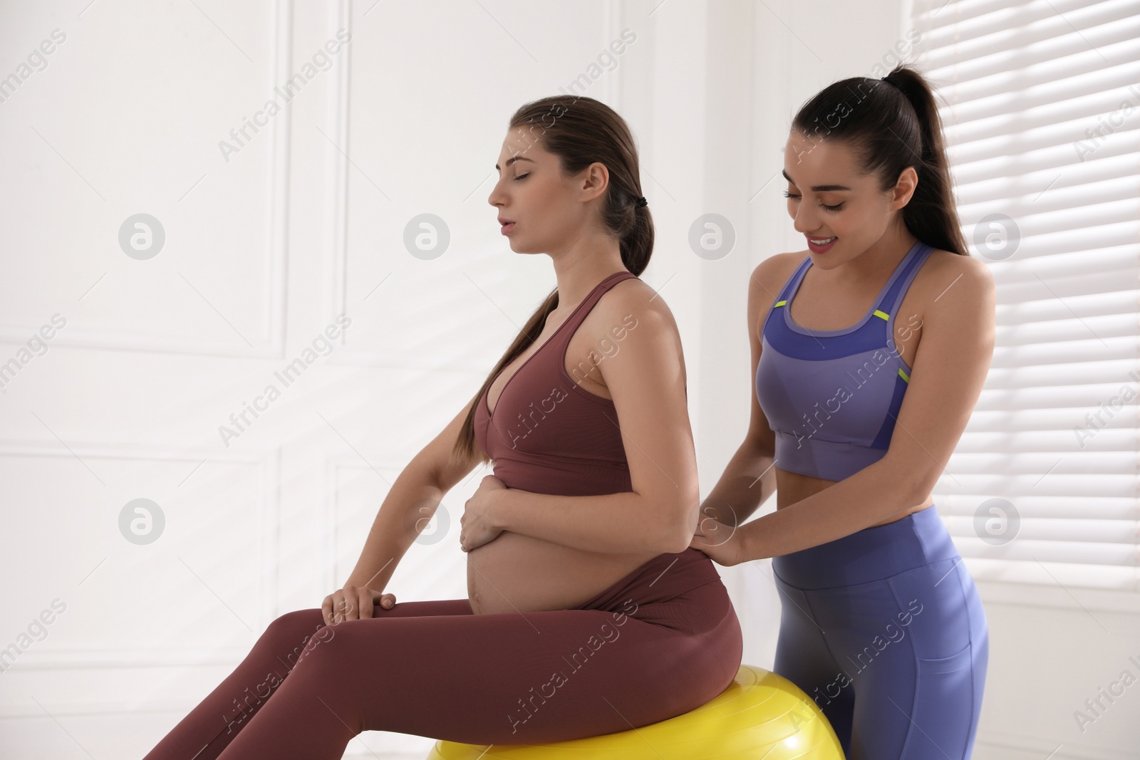Photo of Trainer working with pregnant woman in gym. Preparation for child birth