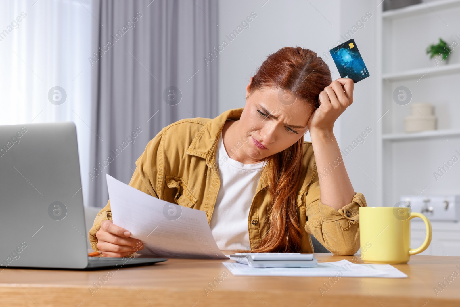 Photo of Woman with credit card using laptop for paying taxes online at home