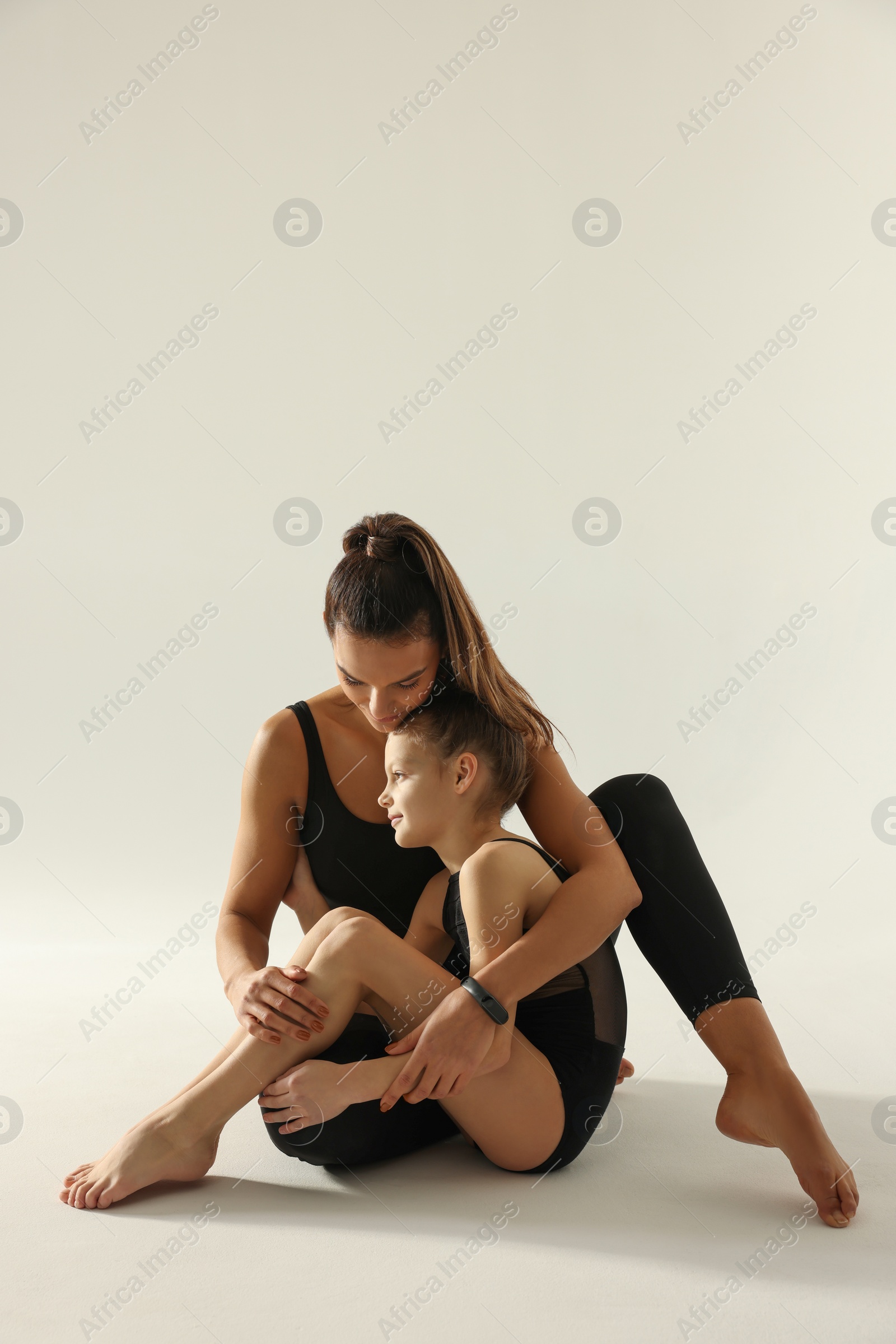 Photo of Little gymnast and her coach sitting on white background