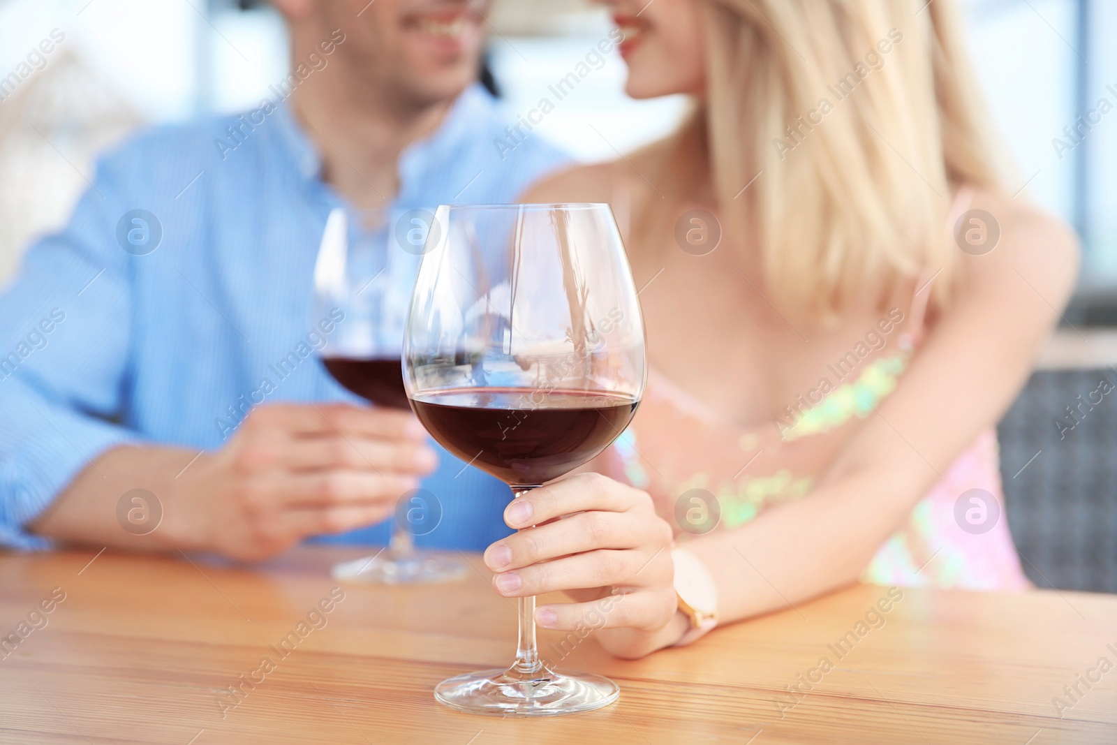 Photo of Young romantic couple with glasses of red wine at table