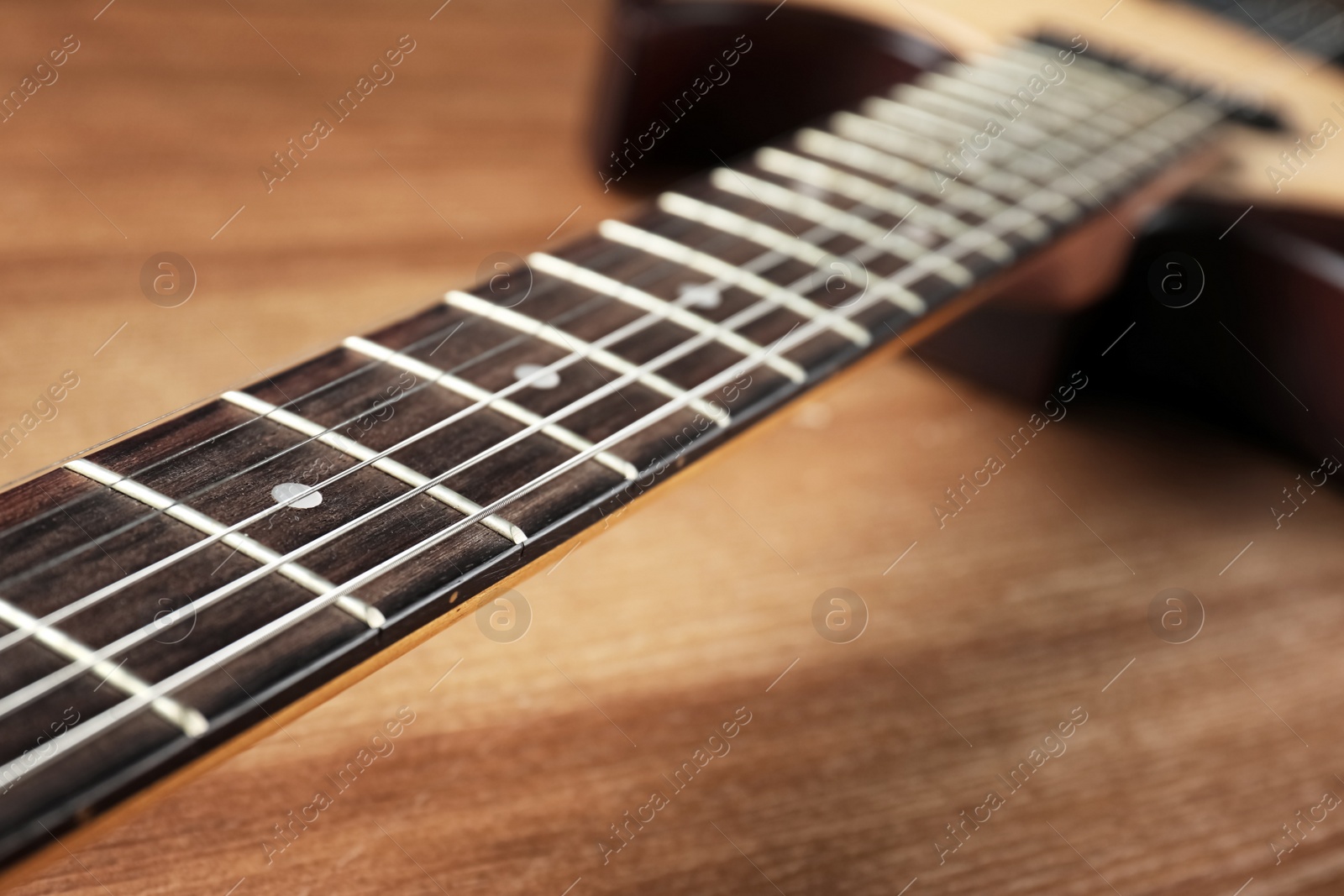 Photo of Modern electric guitar on wooden background, neck with strings in focus