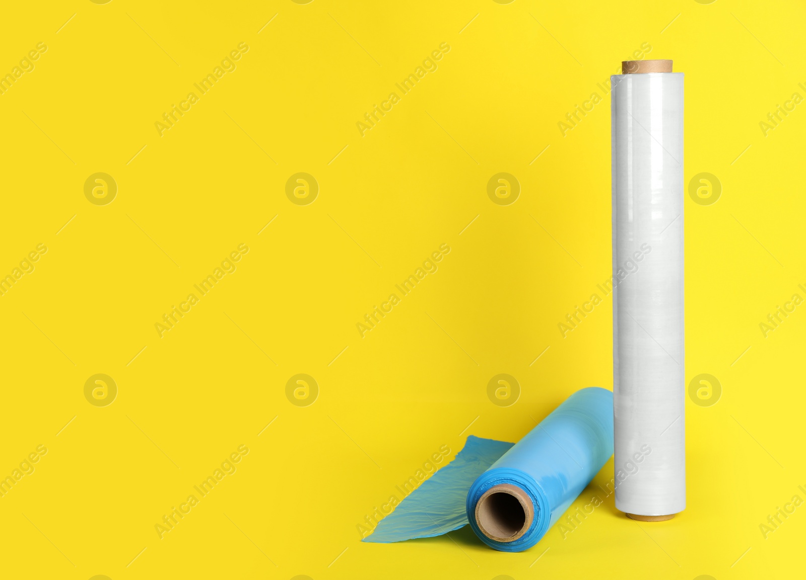 Photo of Rolls of different stretch wrap on yellow background. Space for text