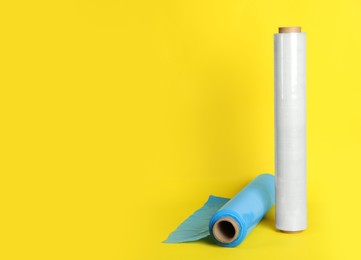 Photo of Rolls of different stretch wrap on yellow background. Space for text