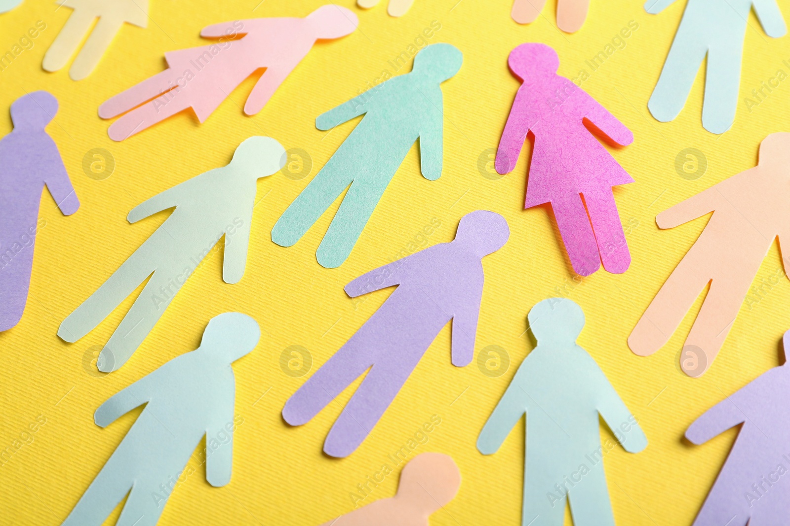 Photo of Many different paper human figures on yellow background. Diversity and inclusion concept
