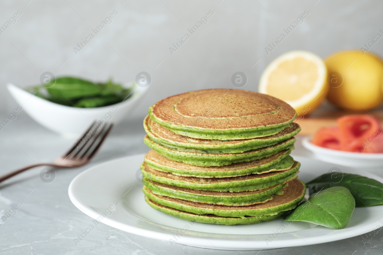 Photo of Tasty spinach pancakes on light grey table, closeup