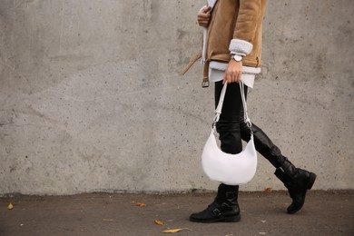 Photo of Stylish woman with trendy white baguette bag on city street, closeup