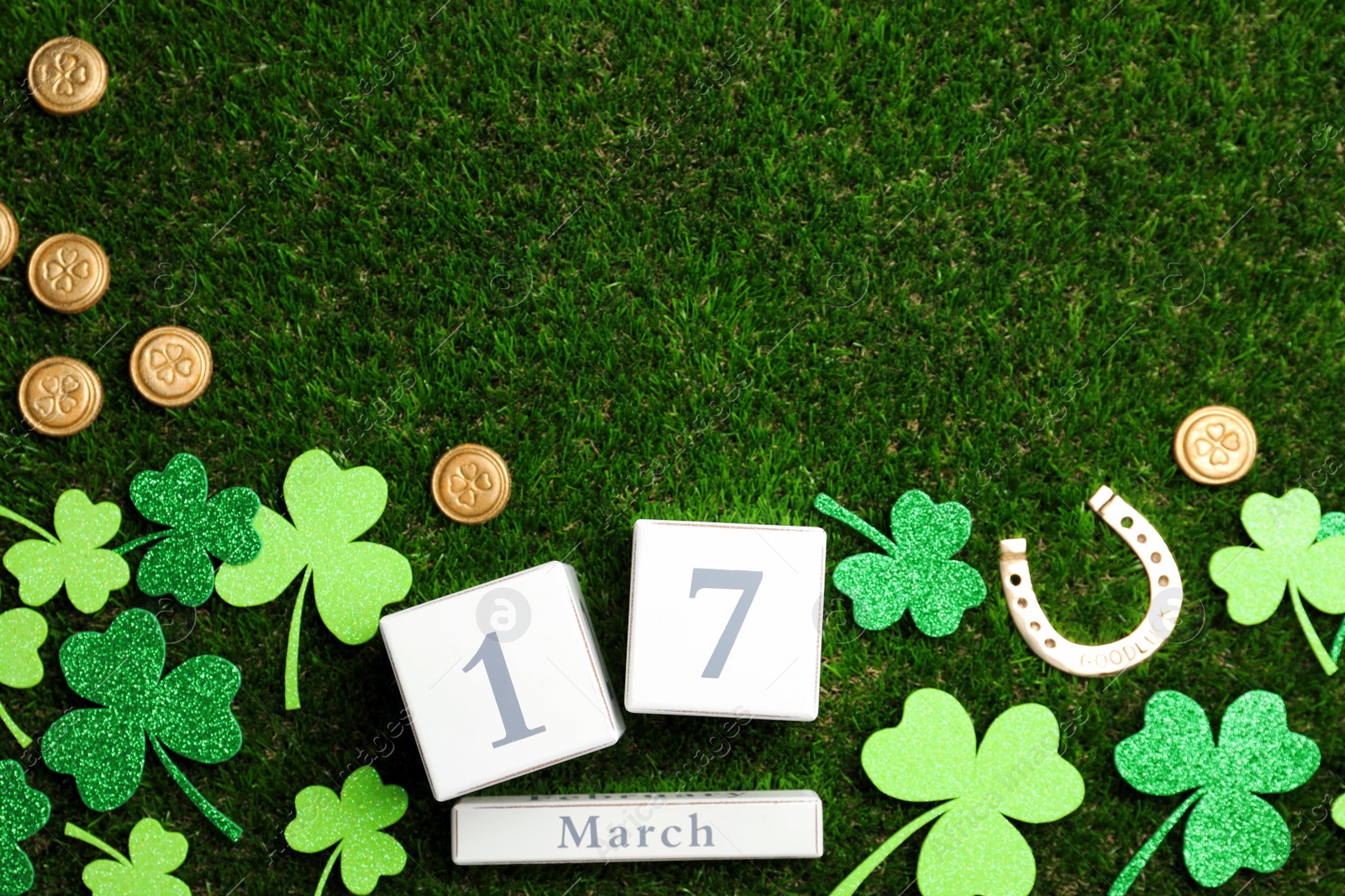 Photo of Flat lay composition with horseshoe and block calendar on grass, space for text. St. Patrick's Day celebration