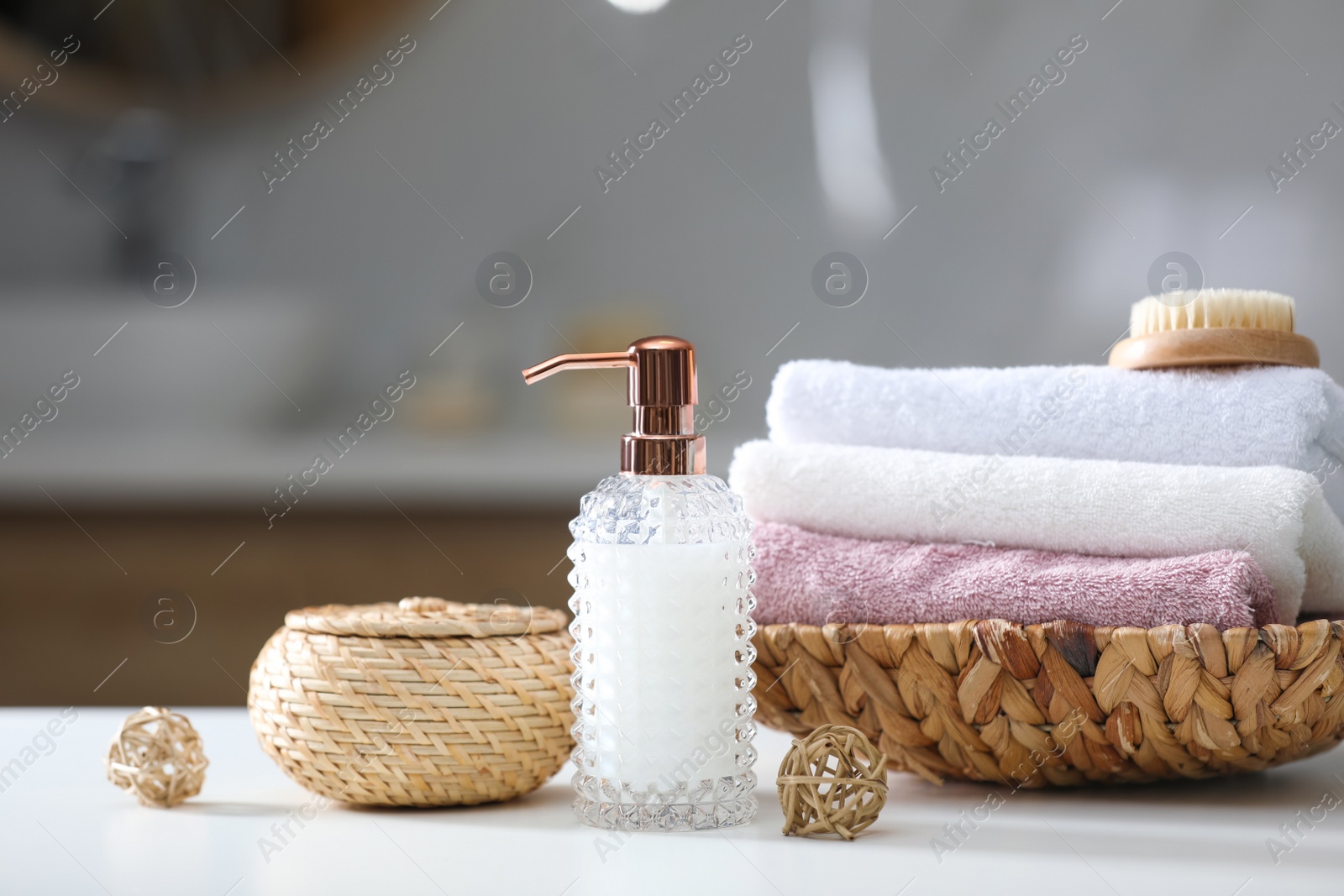 Photo of Soap dispenser, towels and brush on white table indoors