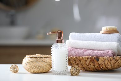 Soap dispenser, towels and brush on white table indoors