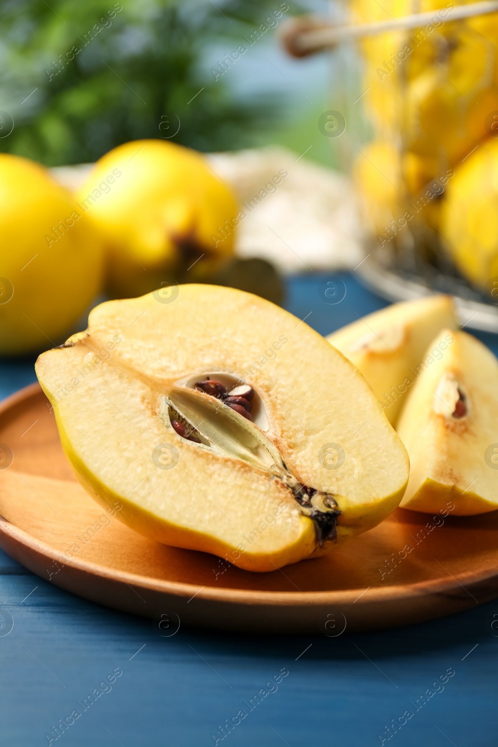 Photo of Tasty ripe quince fruits and knife on blue wooden table, closeup