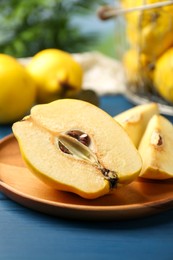 Tasty ripe quince fruits and knife on blue wooden table, closeup