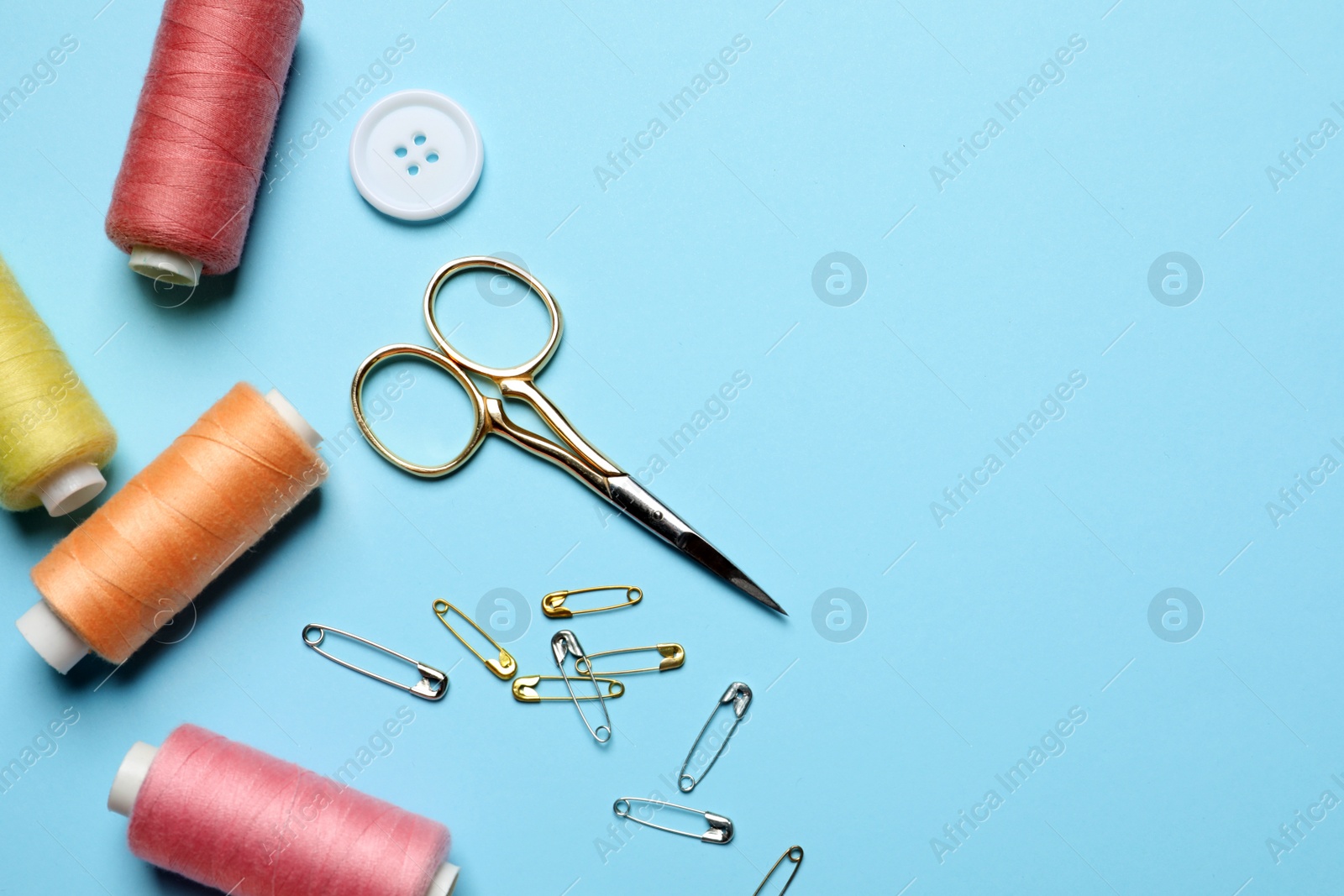 Photo of Flat lay composition with scissors and other sewing accessories on light blue background. Space for text