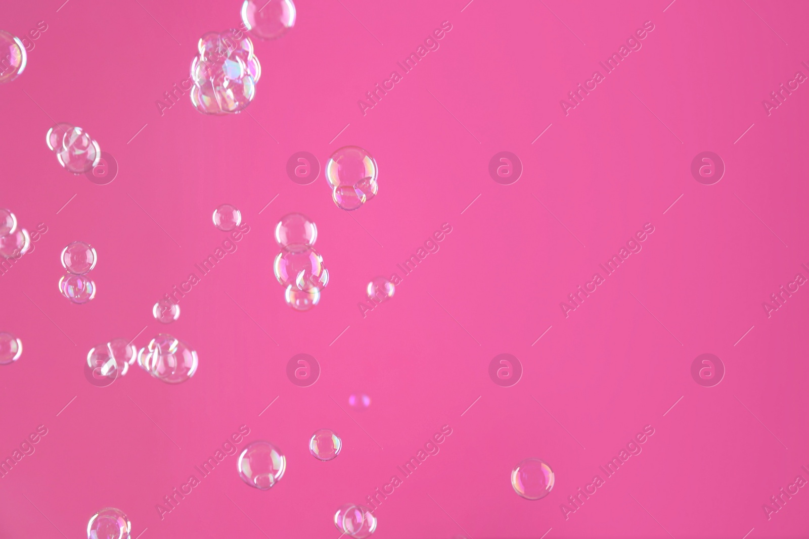 Photo of Beautiful transparent soap bubbles on pink background, space for text