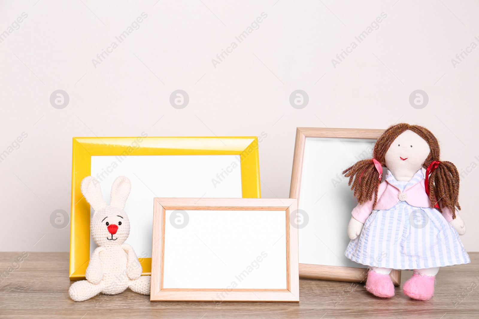 Photo of Photo frames and adorable toys on table against light background, space for text. Child room elements