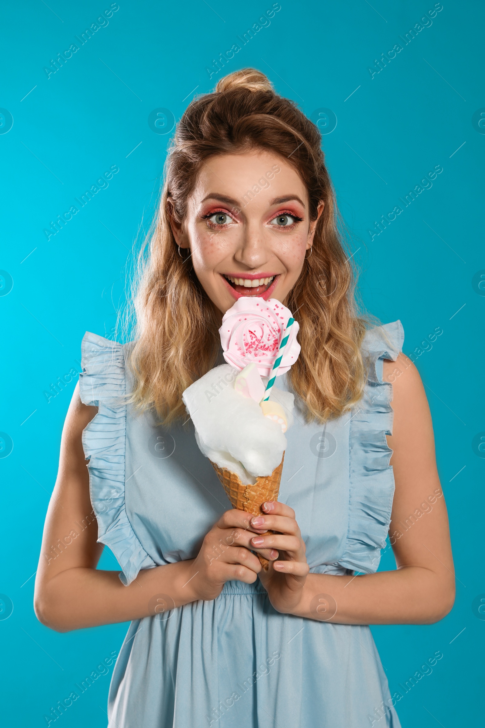 Photo of Portrait of young woman holding cotton candy dessert on blue background