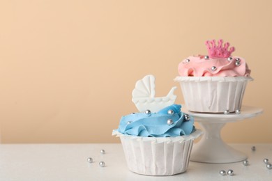 Delicious cupcakes with pink and light blue cream on white table, space for text. Baby shower party