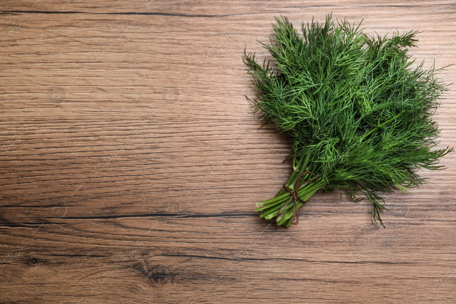 Photo of Bunch of fresh dill on wooden table, top view. Space for text