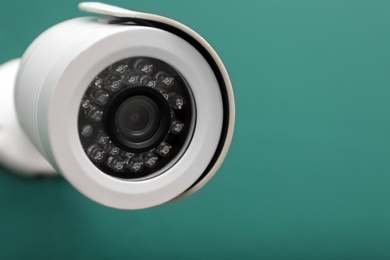 Photo of Modern CCTV security camera on green wall. Space for text