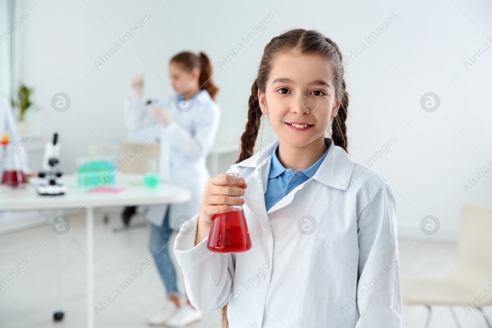Photo of Schoolgirl holding conical flask at chemistry class