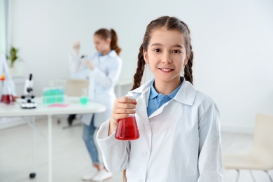 Schoolgirl holding conical flask at chemistry class
