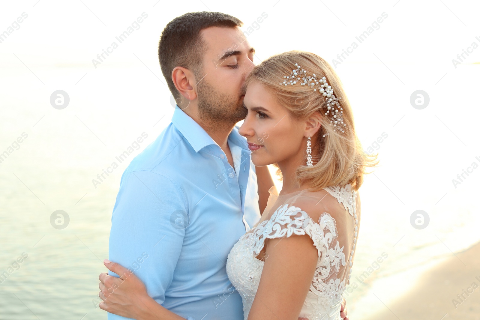 Photo of Wedding couple. Groom kissing bride on beach