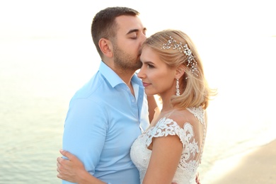 Wedding couple. Groom kissing bride on beach