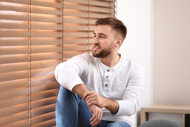 Handsome young man near window at home