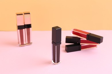 Photo of Many different lip glosses on color background