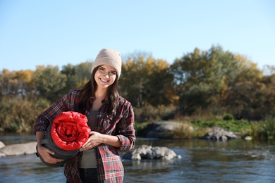 Photo of Female camper with sleeping bag near pond. Space for text