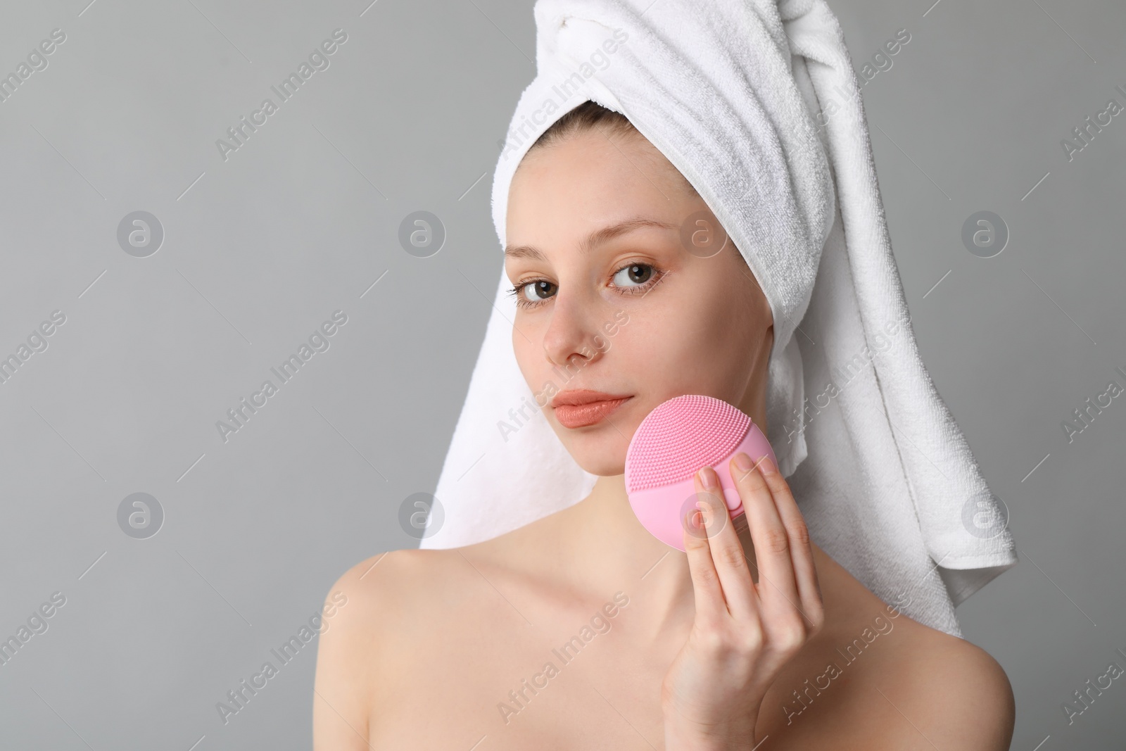 Photo of Washing face. Young woman with cleansing brush on grey background