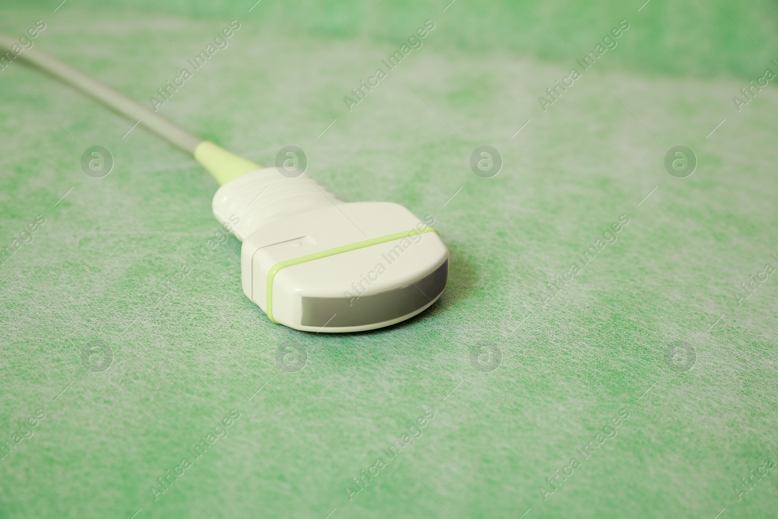 Photo of Ultrasonic transducer on green examination table, closeup. Ultrasound device